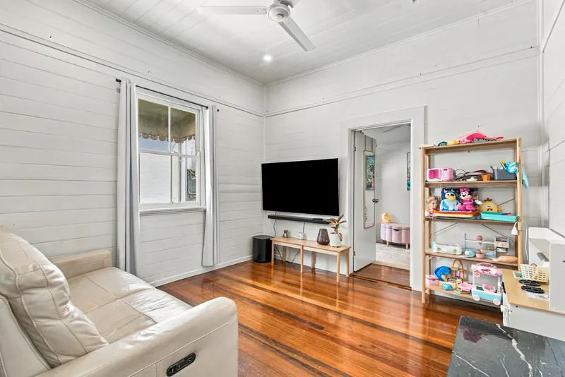 Lounge with sofa, wall-mounted TV and ceiling fan